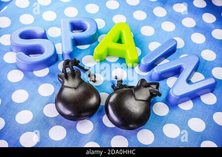 Closeup shot of the word "Spain" made of plastic letters and castanets on blue dotted background Stock Photo