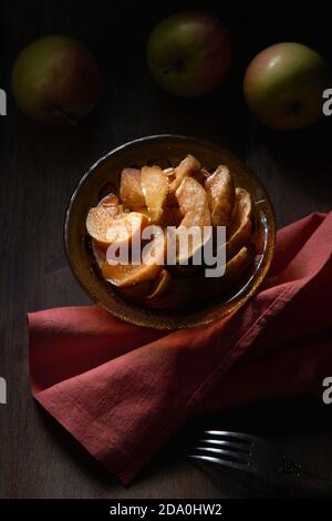 From above of bowl with delicious sweet sliced baked apples served on table with fork and napkin Stock Photo