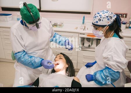Unrecognizable orthodontist in sterile gloves putting transparent braces on teeth of Woman in clinic Stock Photo