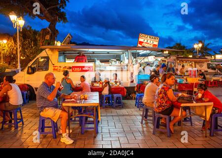 Outdoor dining in a plaza among roulotte food vans at Papeete on the island of Tahiti, Tahiti Nui, Society Islands, French Polynesia, South Pacific. Stock Photo