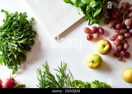 Flatlay with various vegetarian cooking ingredients: grapes, lettuce, apples and herbs Stock Photo