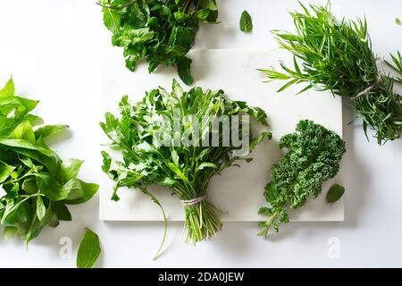 Flat lay with various herbs and lettuce and marble cutting board Stock Photo
