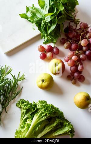 Flatlay with various vegetarian cooking ingredients: grapes, lettuce, apples and herbs Stock Photo