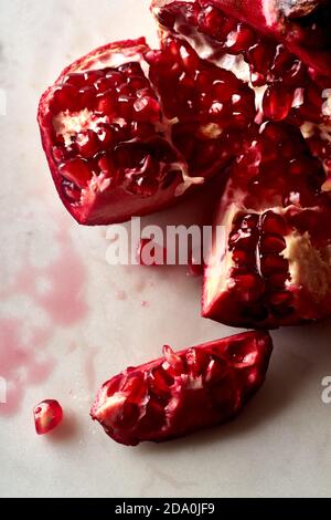 Fresh ripe halved pomegranate and seeds on white marble background Stock Photo