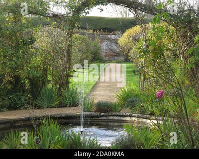 A view in the walled garden at Rousham House, Oxfordshire, with its smalll pond & fountain, herbaceous borders and formal pathways. Stock Photo
