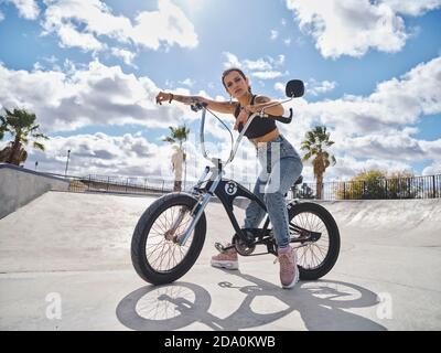 Side view of determined tattooed female in stylish outfit sitting on BMX bicycle in skate park and looking at camera Stock Photo Alamy