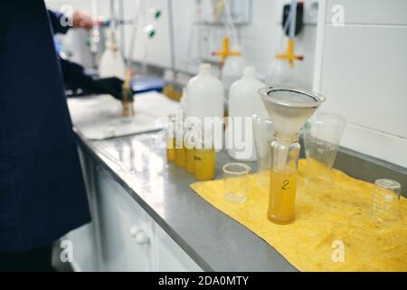 Funnel in glass vial with yellow chemical liquid placed on table in modern laboratory Stock Photo