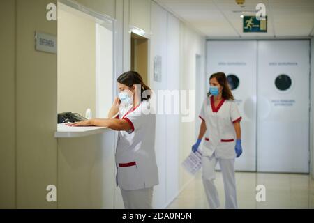 Unrecognizable medical staff talking on telephone near female partner in uniform walking in hospital corridor with paper Stock Photo