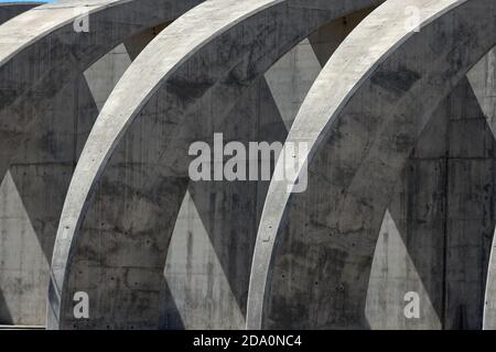 Detail of contemporary concrete construction with curved arched columns illuminated by sunlight in city Stock Photo