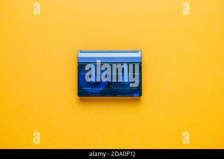 Top view of obsolete transparent audio tape cassette placed on bright yellow background Stock Photo