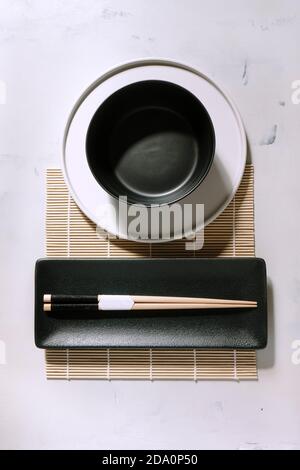 Top view of empty bowl placed on bamboo mat near wooden chopsticks on table Stock Photo