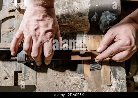 Crop male woodworker standing at old workbench and working with lumber details in grungy workshop Stock Photo