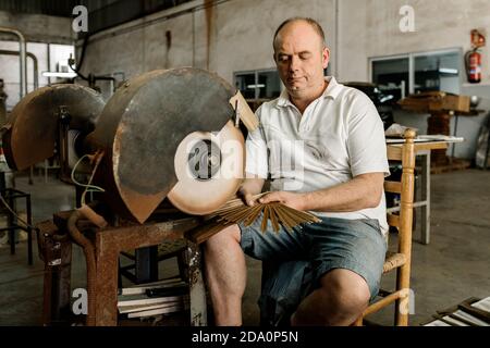 Craftsman using grinding machine while making creative wooden folding fan in shabby workshop Stock Photo