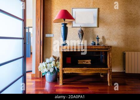 Apartment hallway with shiny wooden parquet and flowers near table with antique statues Stock Photo
