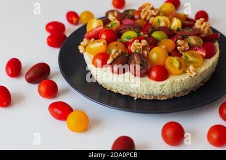 Palatable aromatic homemade quiche with colorful fresh tomatoes and walnuts served on black ceramic plate Stock Photo