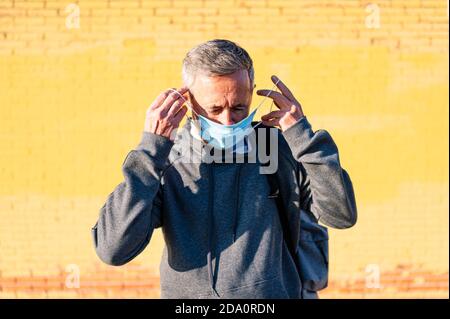 Portrait of senior retired man putting on face mask in sportswear Stock Photo