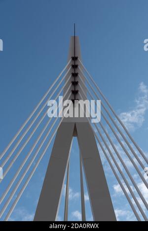 From below of white contemporary suspension bridge with high column connecting many cables together against blue sky Stock Photo