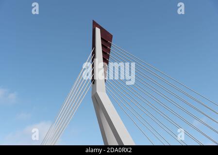 From below of white contemporary suspension bridge with high column connecting many cables together against blue sky Stock Photo