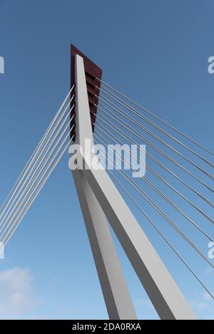 From below of white contemporary suspension bridge with high column connecting many cables together against blue sky Stock Photo