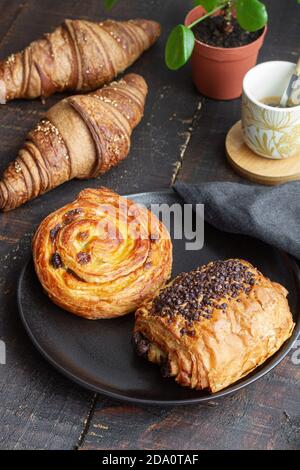 From above delicious homemade croissants arranged on wooden table with tasty bun with chocolate and roll with raisin Stock Photo