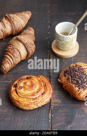 From above delicious homemade croissants arranged on wooden table with tasty bun with chocolate and roll with raisin Stock Photo