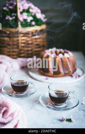 High angle of hot tea in glass cups arranged on table with delicious lemon Bundt cake Stock Photo