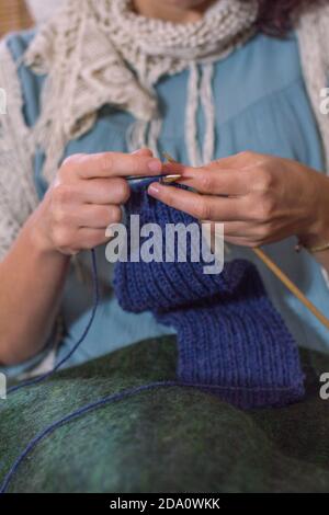 Front view of a woman sat on a rattan chair knitting. Stock Photo