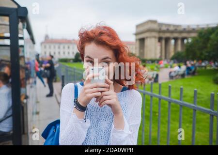 Young female with black hair looking at burning match in hand while standing at wall in room with dim light looking at fire Stock Photo