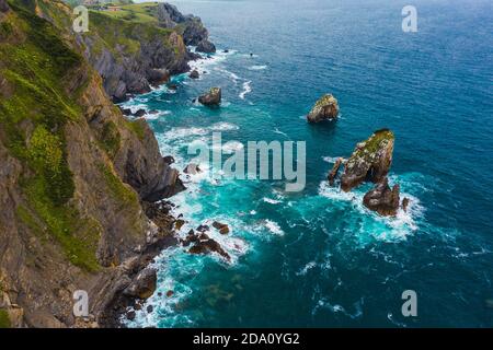 From above of rough mountains near wavy sea with foam on surface in Basque Country Stock Photo