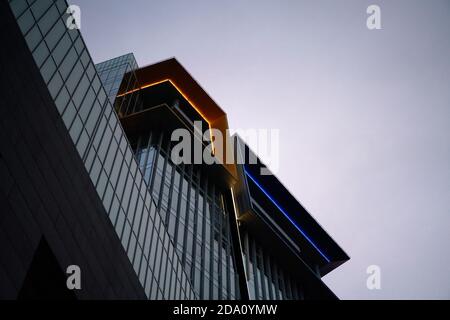 Bottom view of modern building with glass windows, gloomy sky during day Stock Photo