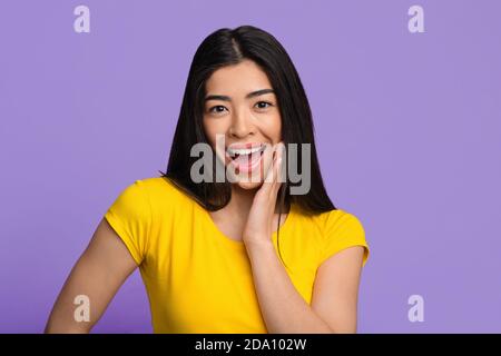 Shocked Asian Female Emotionally Reacting To Surprise, Touching Face With Excitement Stock Photo