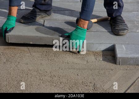 Brick Paver Working. Worker lay paving tiles, construction of brick pavement. Architecture background Stock Photo