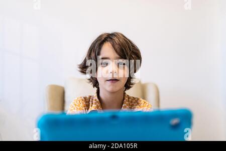 Concentrated child with netbook at table sitting on couch at home Stock Photo