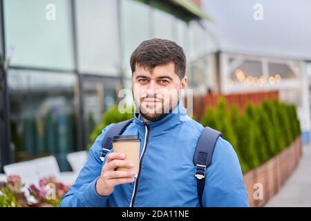 Young man drinks takeaway coffee from paper cup outdoor. Stock Photo