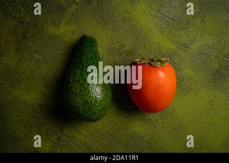 kika persimmon and avocado on wooden background Stock Photo