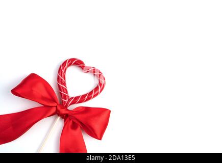 Bow with a heart-shaped Lollipop on a light background. Stock Photo