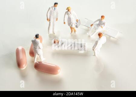 closeup of the team of miniature figurines of special doctor forces and normal doctors having a meeting around a sick person on a strecher with danger Stock Photo