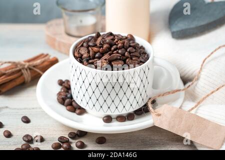 Cozy coffee background with whole coffee beans, cinnamon and candles on a light wooden background. Stock Photo