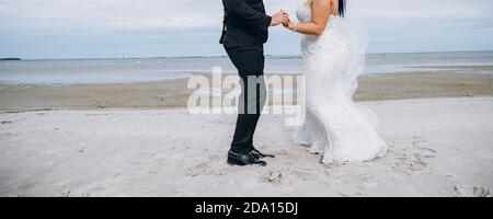 Wedding couple dancing at the beach, young bride wears white dress and long veil. Stock Photo