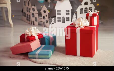 Beautiful Christmas gift boxes on the floor near the Christmas tree in the room. Holidays, gifts, new year and celebration concept - gift boxes on sheepskin. Stack of wrapped christmas gifts. Stock Photo