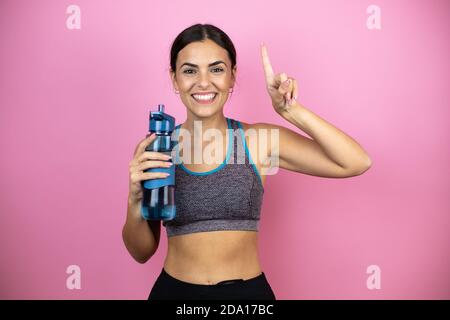 Young beautiful woman wearing sportswear over isolated pink background pointing finger up surprised. Stock Photo