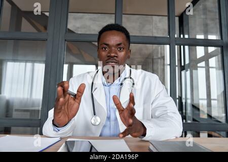 Black male doctor talking to web cam during virtual telemedicine advice. Stock Photo