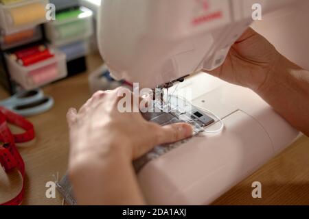 Woman hands using the sewing machine to sew the face mask Stock Photo