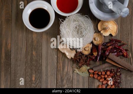 Chinese cooking spices with soy sauce, chili oil, anise spice, noodles, dried peppers and mushroom  on a wooden table from Sichuan Stock Photo