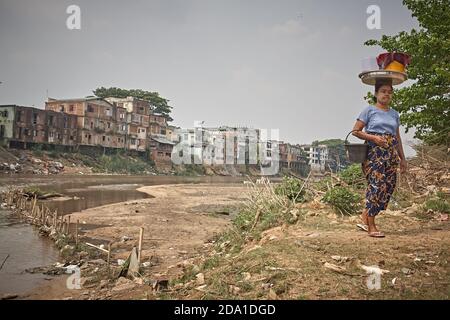 Mae Sot, Thailand. April 2012. A woman walks by the river that serves as the border with Myanmar. Stock Photo