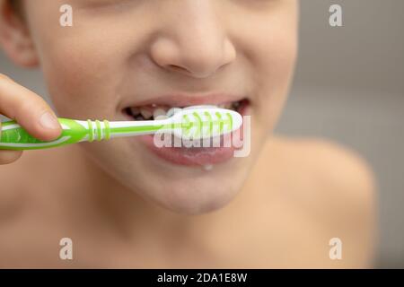Dental education in the family, a boy with joy 10 years old, washing his teeth with toothpaste and a toothbrush in the bathroom. Healthy teeth concept Stock Photo