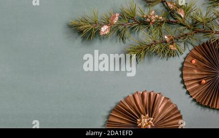 Golden paper fans and Christmas tree branch on the green background. Nice design for your greeting card or party invitation. Stock Photo
