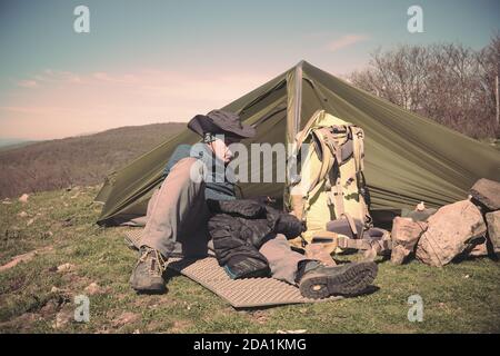 man with hat resting near his tent in Nebrodi Park, Sicily Stock Photo