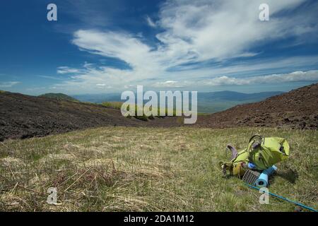 green backpack in mountain landscape of Etna Park, Sicily Stock Photo