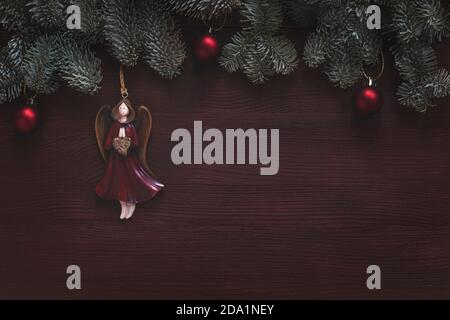 christmas angel and baubles on fir tree branches , holiday background on dark brown wood Stock Photo